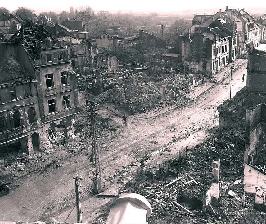 Kreuzung, Gebäude drumherum teilst oder vollkommen zerstört. Einzelner Radfahrer auf der Kreuzung.