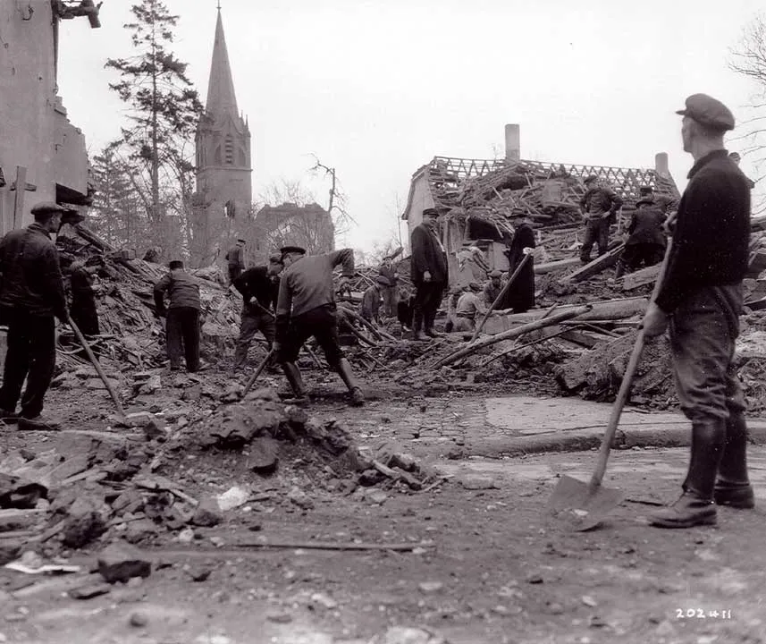 Männer stehen zwischen den Trümmern und Räumen diese weg mit Schaufeln.