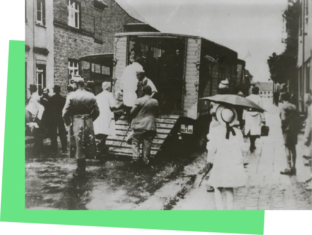 Zwei Laster voller Menschen, in die Menschen geführt werden. Daneben Schaulustige.